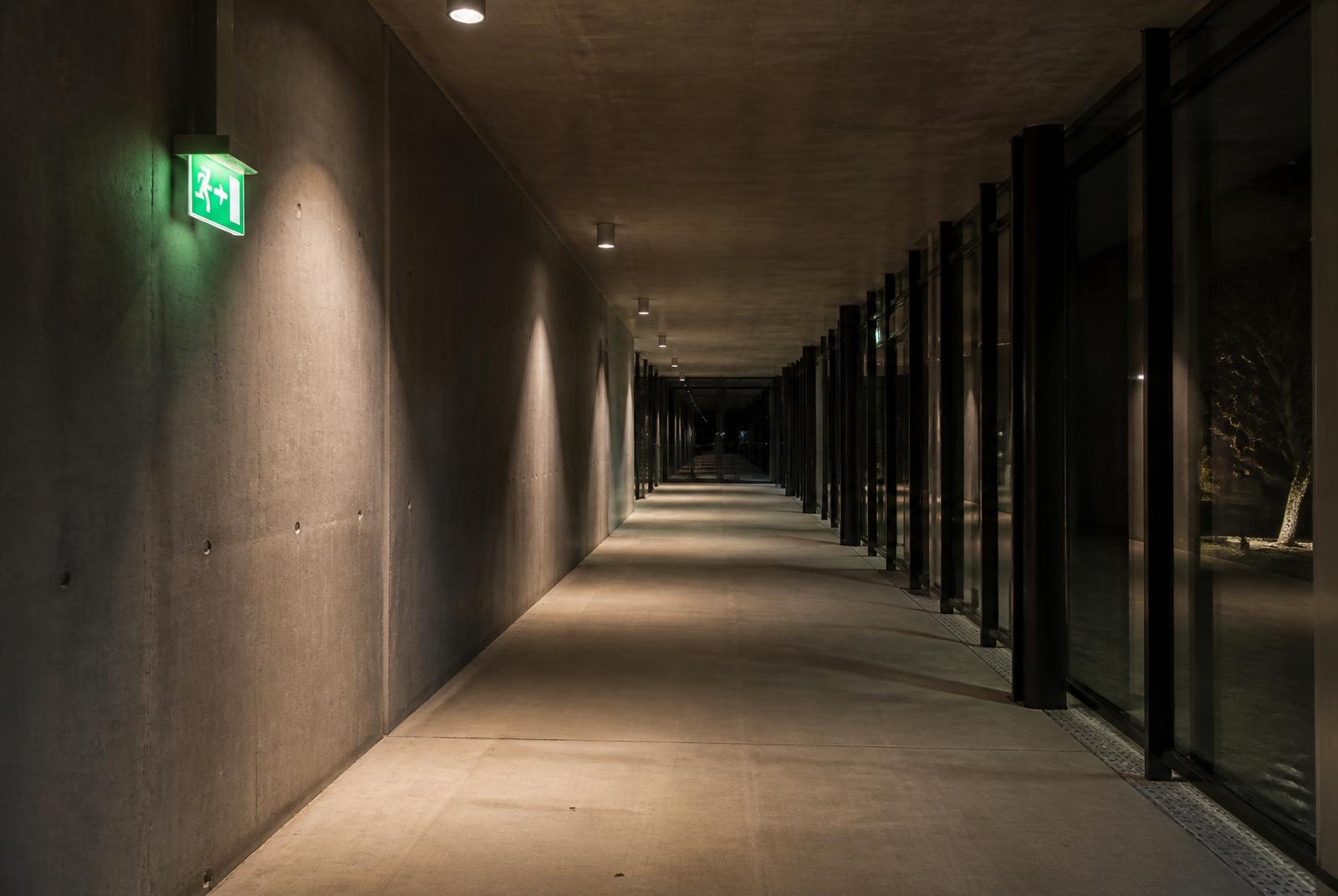 Couloir de bâtiment sécurisé avec signalétique lumineuse de sortie de secours.